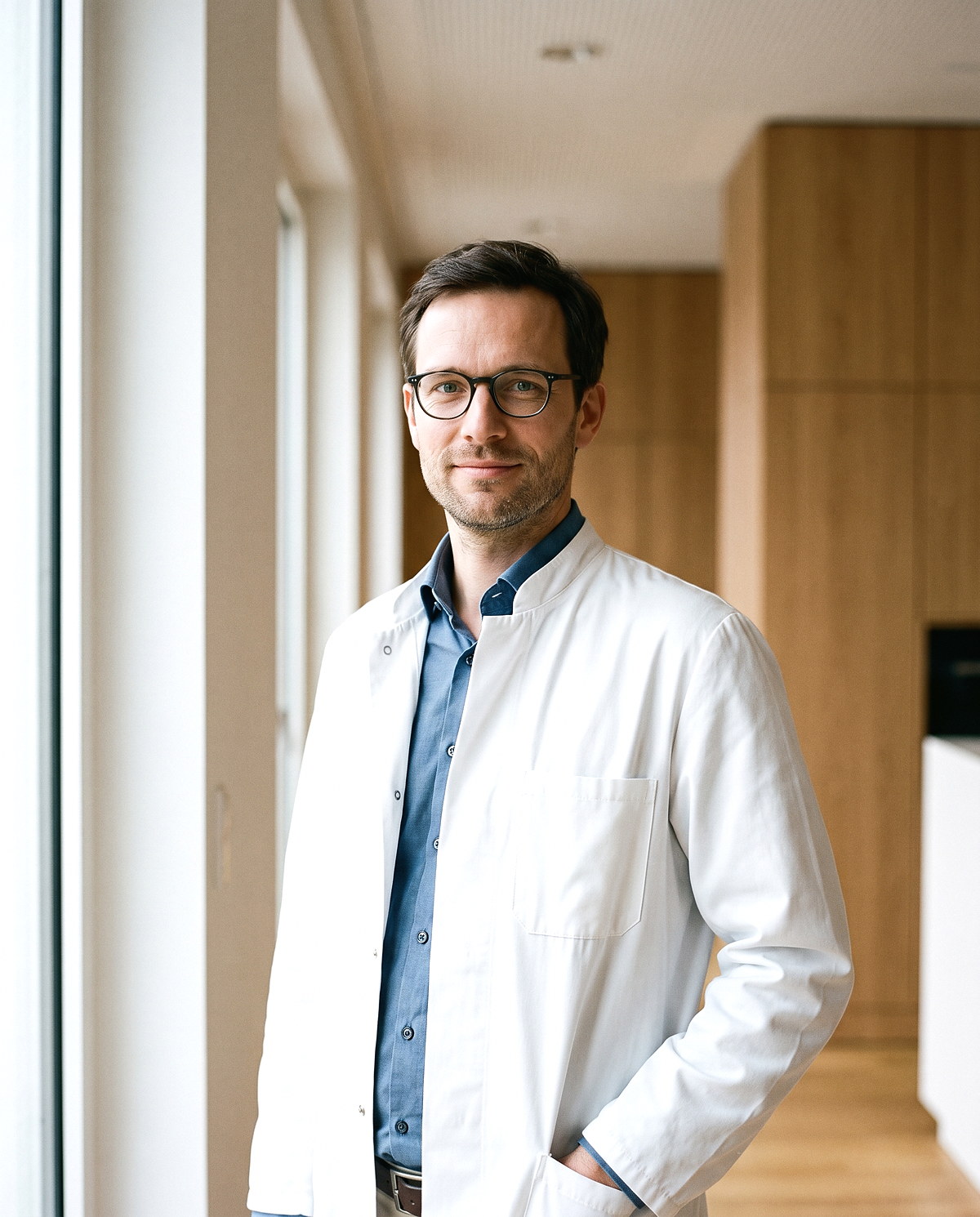 Dr. med. Jonas Keller in der Praxis am Fenster