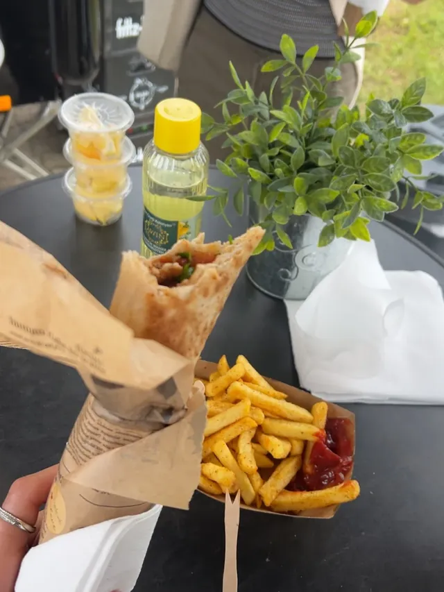 Wrap und Pommes auf dem Tisch neben dem Trailer